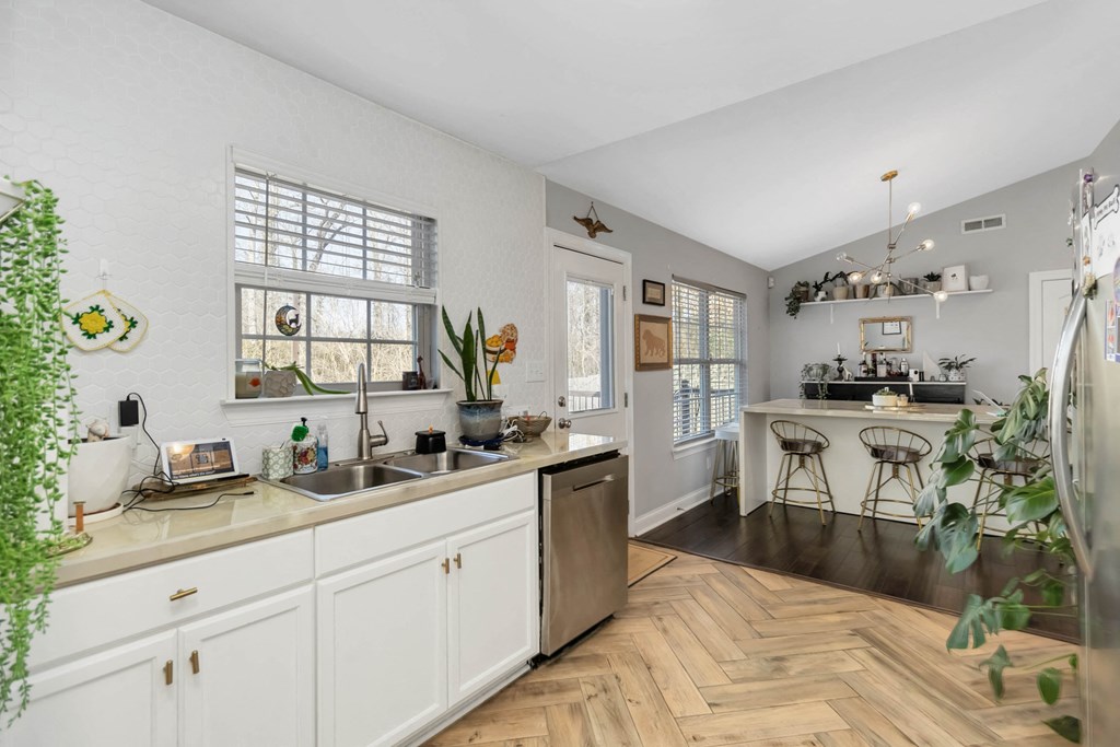 A kitchen with white cabinets and a wooden floor.