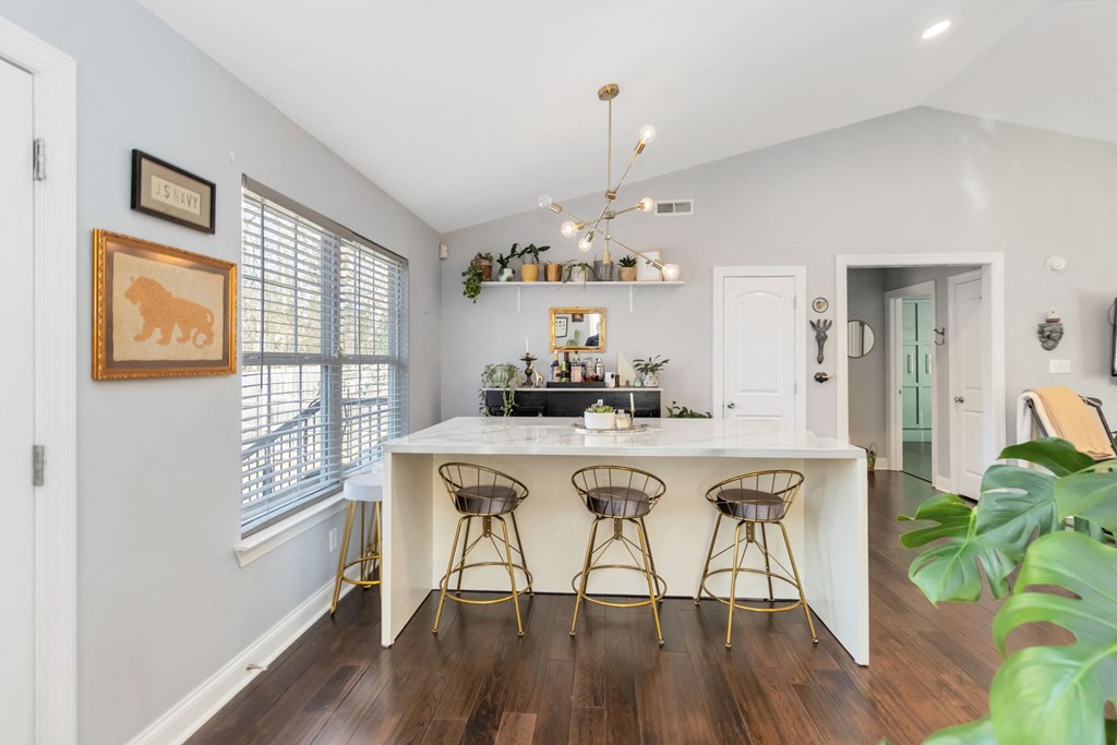 A kitchen with a white counter and bar stools.