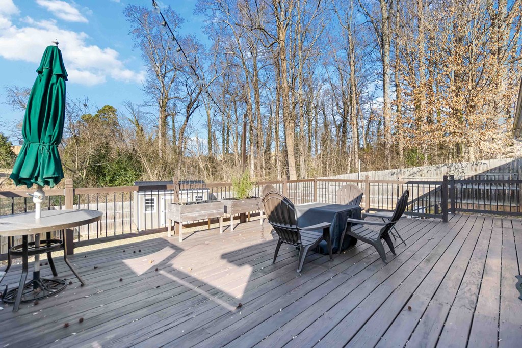 A wooden deck with a table and chairs and a green umbrella.