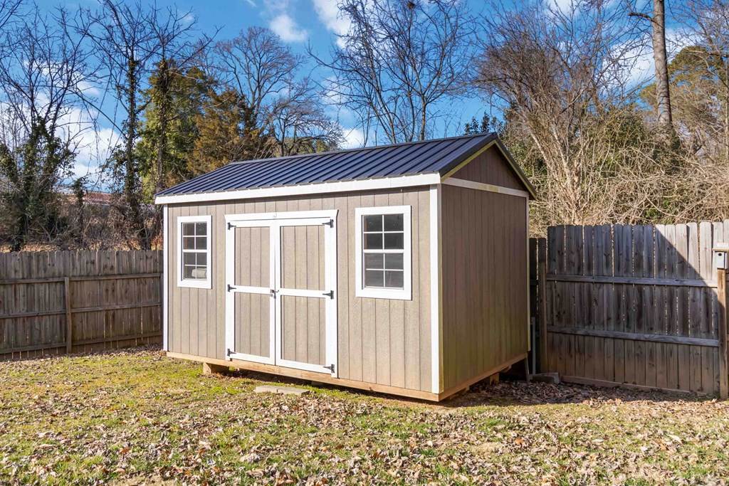 A small wooden shed with a grey roof and white trim.