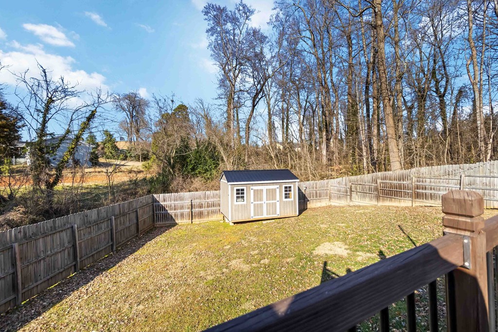 A small house is surrounded by a fence in a grassy backyard.