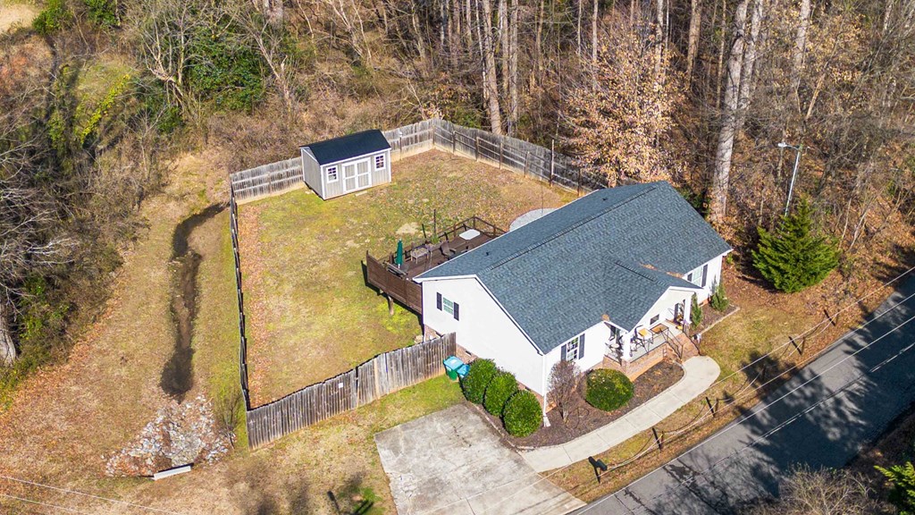 A house with a grey roof is surrounded by a fence.