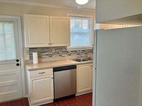 A kitchen with white cabinets and a white refrigerator.