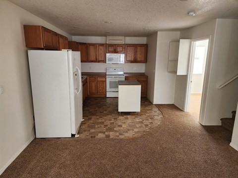 A kitchen with white appliances and brown cabinets.