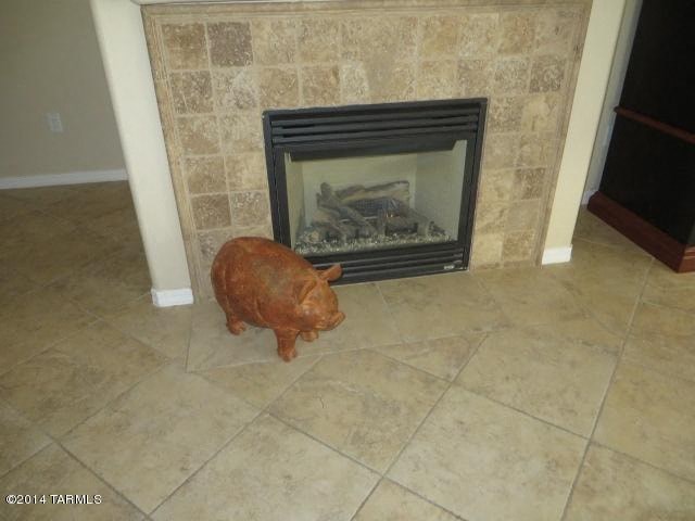 A piggy bank is standing in front of a fireplace.