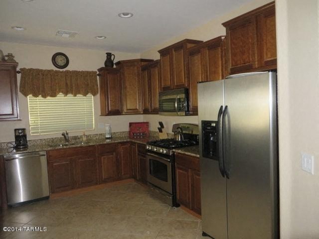 A kitchen with wooden cabinets and a stainless steel refrigerator.