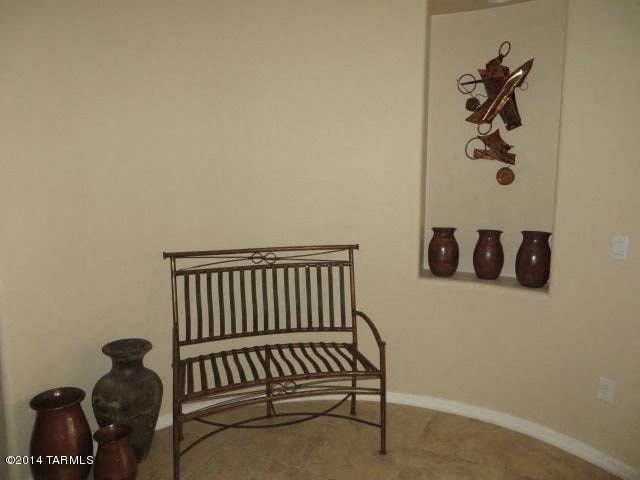 A chair sits in a room with a wall hanging and vases.