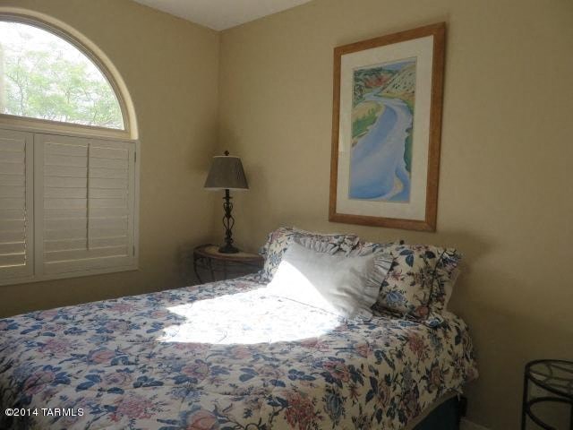 A bedroom with a floral bedspread and a framed picture of a river.