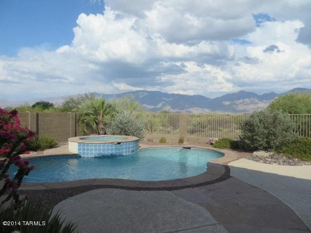 A pool surrounded by a fence with mountains in the background.