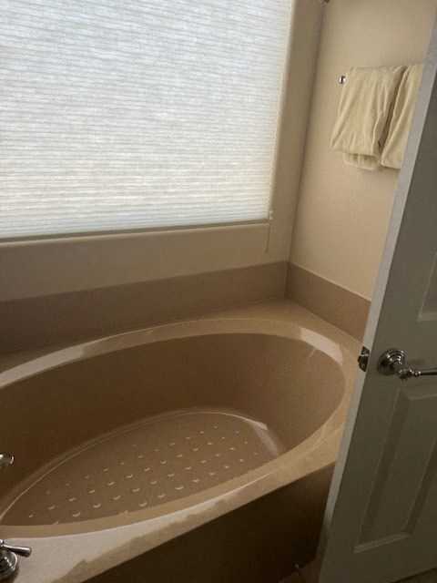 A bathroom with a tub and a towel hanging on the wall.