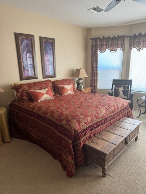 A bed with a red and gold comforter is in the center of a room with a chair and a window.