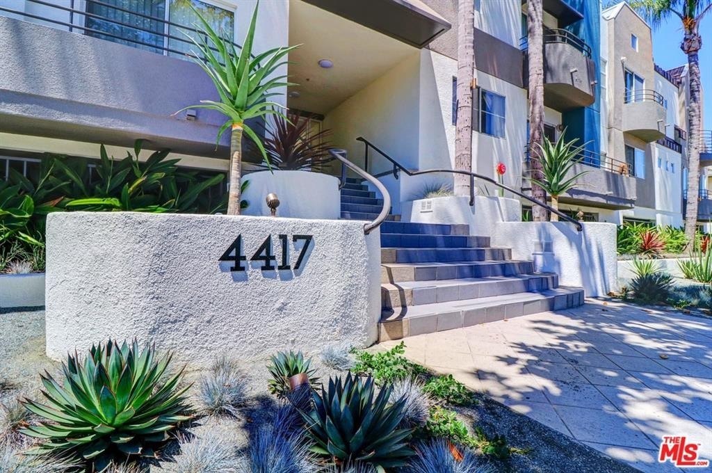 A concrete block with the number 4417 on it is in the foreground of a building with a staircase.