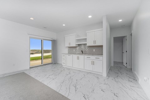 A kitchen with white cabinets and marble flooring.