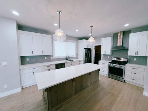 A kitchen with white cabinets and a large island.