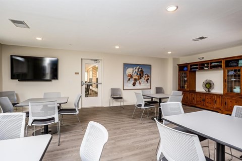 A room with a white table and chairs, a television, and a painting on the wall.