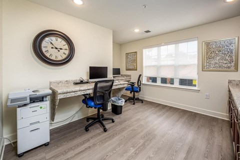 A room with a desk, chairs, and a clock on the wall.