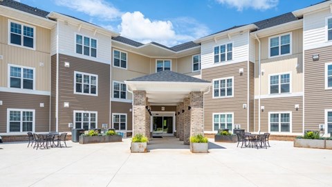 A large, multi-story apartment complex with a central courtyard and seating area.