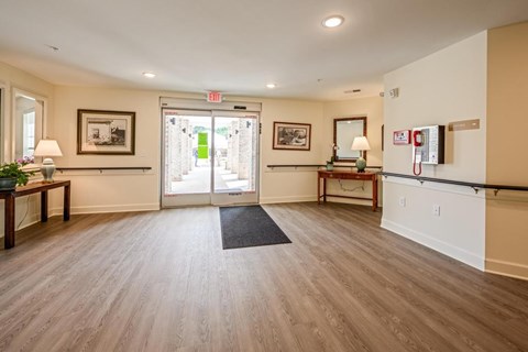 A hallway with a black mat on the floor and a glass door at the end.
