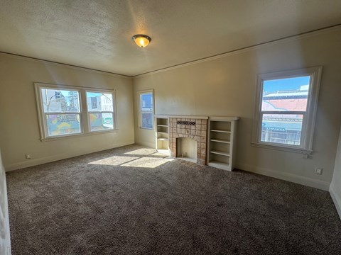 A room with a carpeted floor and a window overlooking a street.
