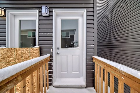 A white door is on the right side of a grey house.