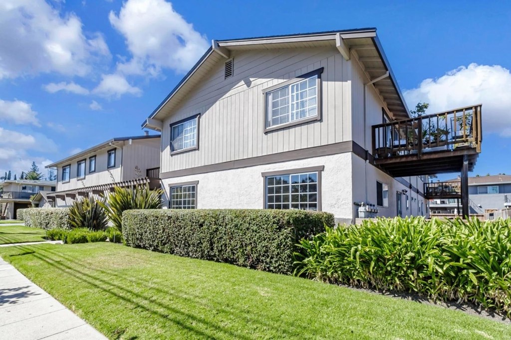 A house with a balcony and a well-manicured lawn.