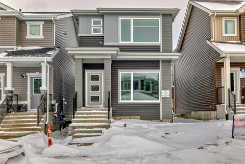 A house with a grey and white exterior is surrounded by snow.