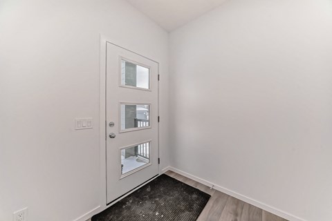 A white door with a glass window is in a room with white walls.