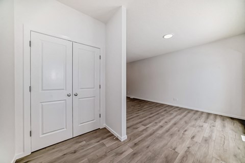 A room with a white door and wooden flooring.
