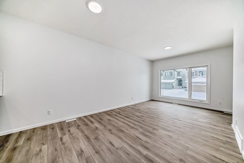 A room with wooden flooring and a window showing a snowy landscape outside.