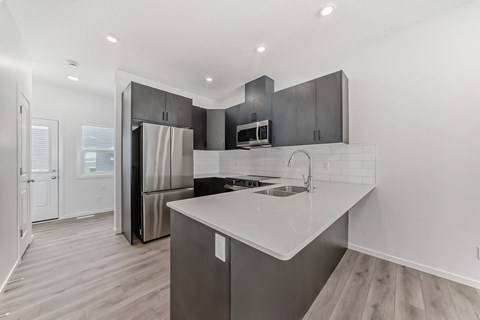 A modern kitchen with a stainless steel refrigerator and a white countertop.