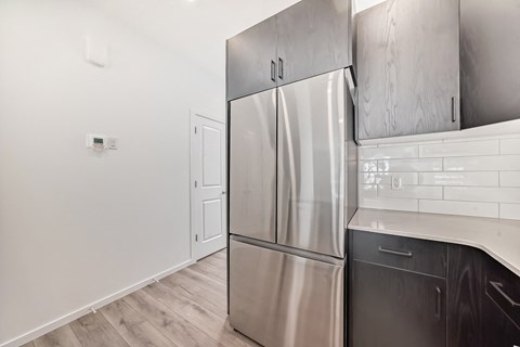 A kitchen with a stainless steel refrigerator and black dishwasher.