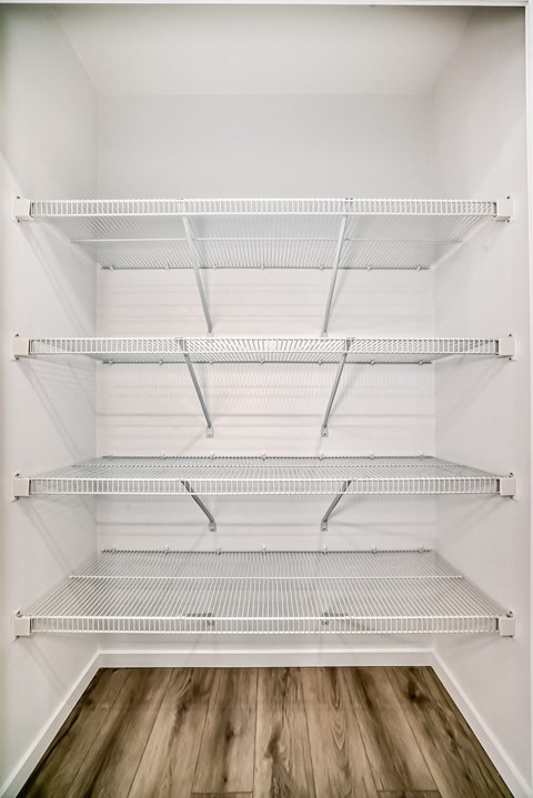 Empty white shelves in a white room with wood flooring.