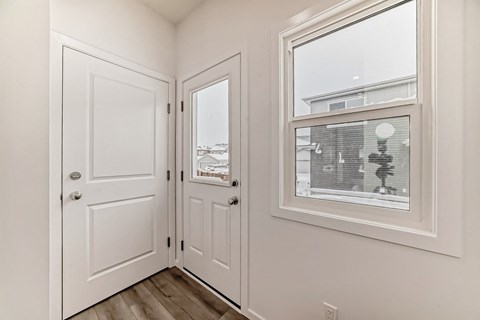 A white door and window in a room with a wooden floor.