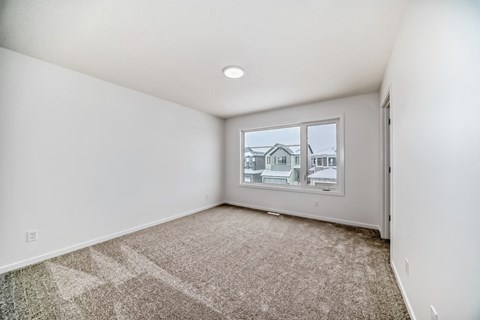 A room with a carpeted floor and a window showing a house outside.