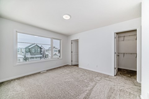 A room with a large window and a door is empty and waiting to be furnished.