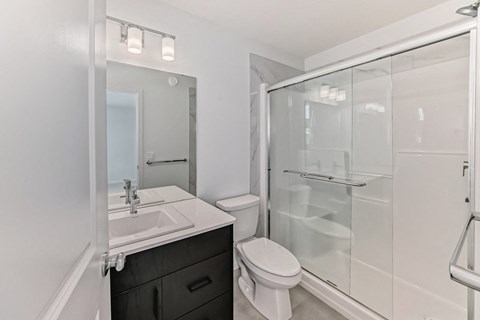 A white bathroom with a sink, toilet, and shower.