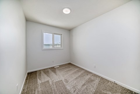 A room with a window and carpeted floor.