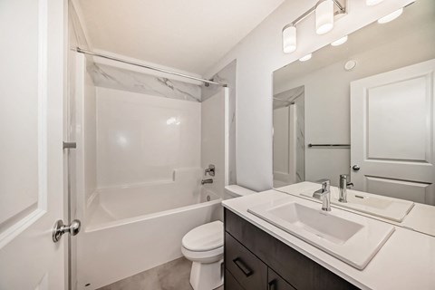 A white bathroom with a toilet, sink, and bathtub.