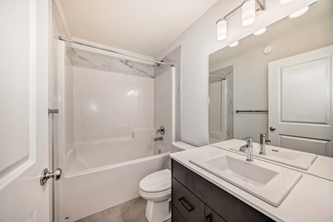 A white bathroom with a toilet, sink, and bathtub.