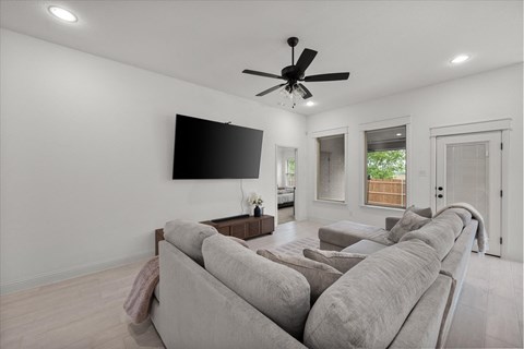 A living room with a grey sofa and a flat screen TV mounted on the wall.