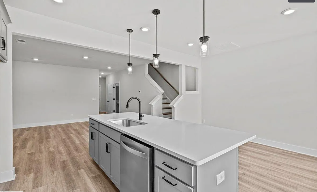 A modern kitchen with a stainless steel sink and wooden flooring.