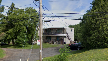 A building with a balcony and a car parked in front.