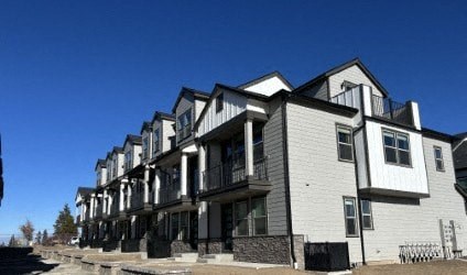 A row of modern townhouses with balconies and black railings.