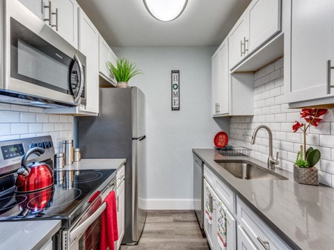 A kitchen with white cabinets and a black fridge.