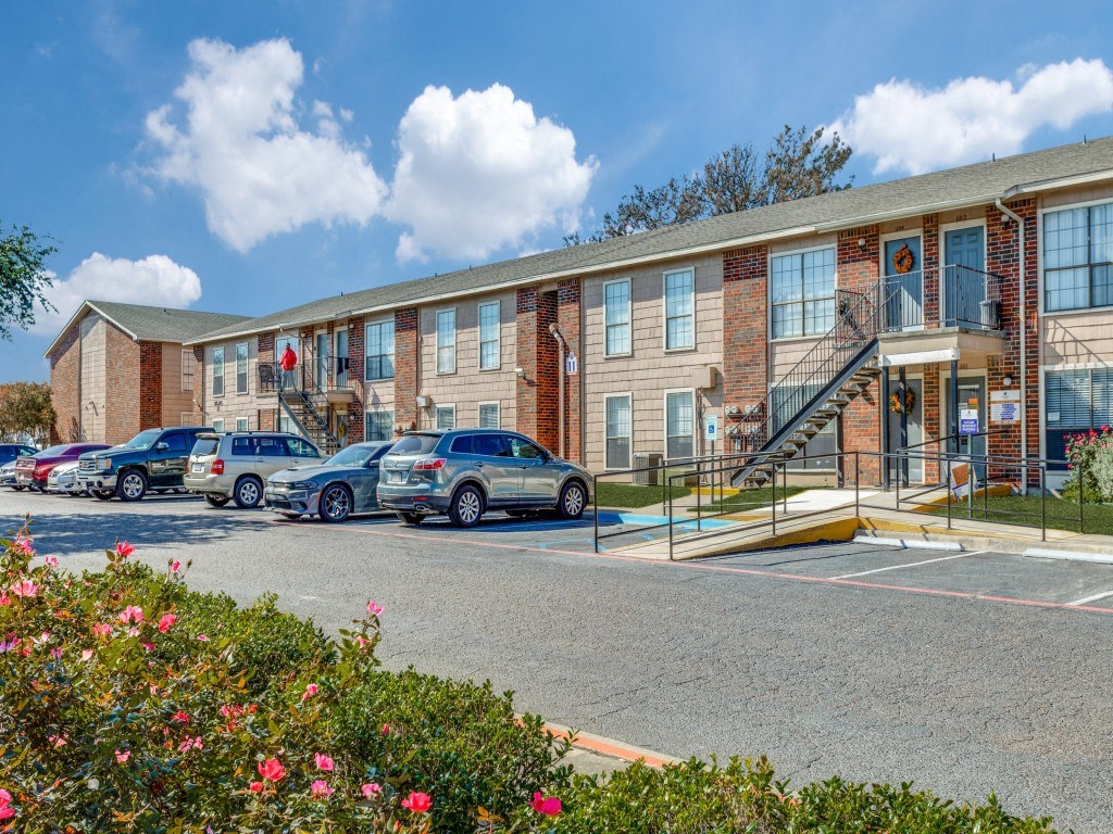 A parking lot with cars and a building in the background.