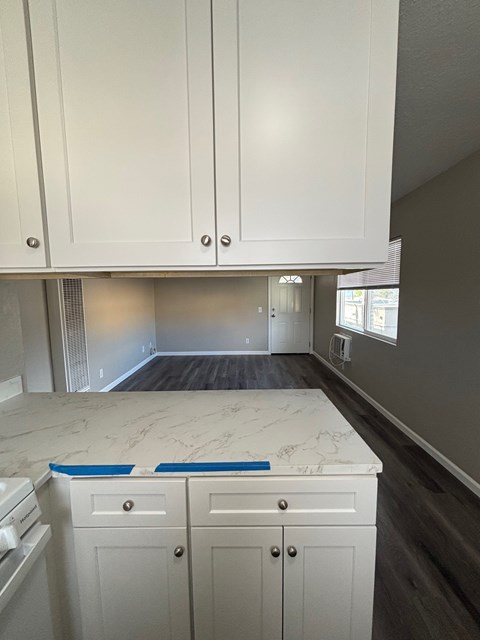A kitchen with white cabinets and a marble countertop.