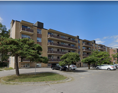 A large apartment building with a parking lot in front.