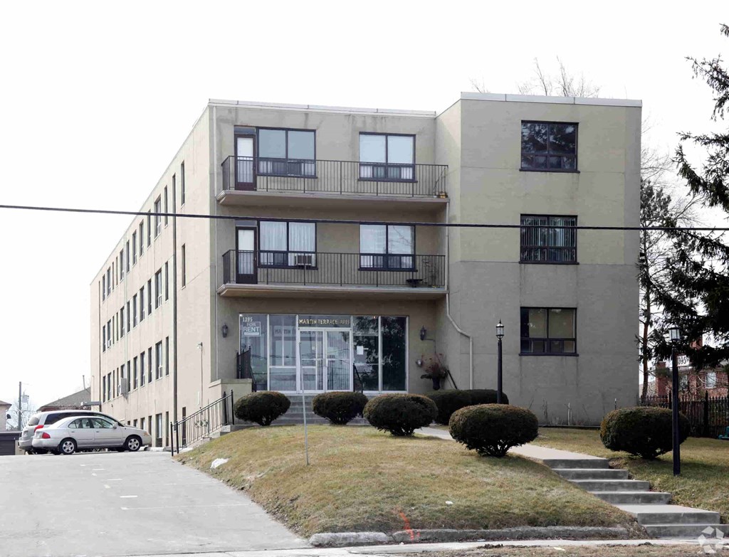 A grey building with a car parked in front.
