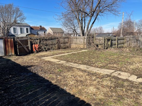 A backyard with a fence and a small patch of grass.