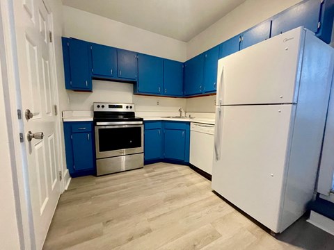 A kitchen with blue cabinets and a white refrigerator.